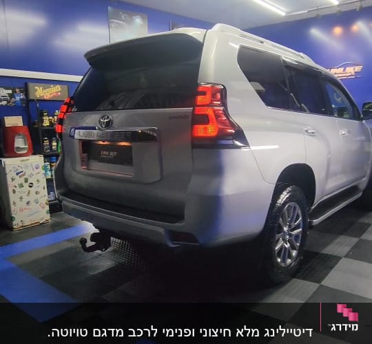 רכב שטח לבן בחדר דיטיילינג עם תאורה חזקה